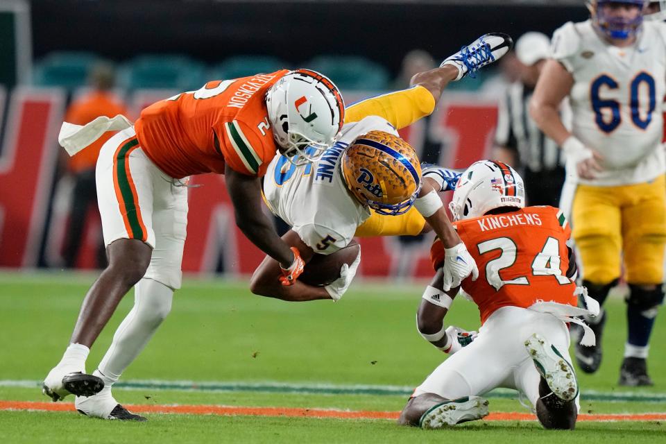 Pittsburgh wide receiver Jared Wayne (5) is tackled by Miami cornerback Tyrique Stevenson (2) and safety Kamren Kinchens (24) during the first half of an NCAA college football game Saturday, Nov. 26, 2022, in Miami Gardens, Fla. (AP Photo/Lynne Sladky)