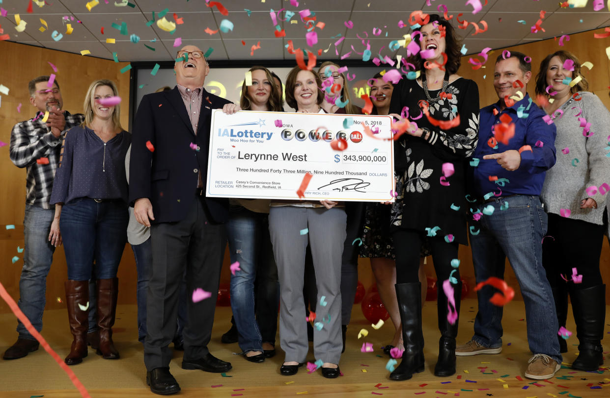 Iowa Lottery CEO Terry Rich, left, presents a check to Lerynne West, of Redfield, Iowa, center, for her share of a nearly $700 million Powerball prize, Monday, Nov. 5, 2018, at the Iowa Lottery headquarters in Clive, Iowa. (AP Photo/Charlie Neibergall)