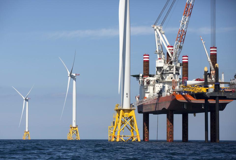 A lift boat, right, that serves as a work platform, assembles a wind turbine off Block Island, Rhode Island.