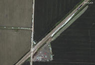 This satellite image provided by Maxar shows an Amtrak train, at right, that derailed a day earlier along the rail line and dozens of cars, heavy lift equipment and rescue vehicles positioned nearby, Tuesday, June 28, 2022, near Mendon, Mo. (Satellite image ©2022 Maxar Technologies via AP)