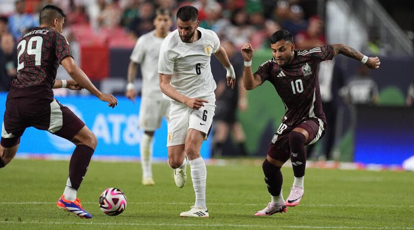 Uruguay midfielder Rodrigo Bentancur, center, drives between Mexico forward Guillermo Martinez, left, and midfielder Alexis Vega in the second half of an international friendly soccer match Wednesday, June 5, 2024, in Denver. (AP Photo/David Zalubowski)