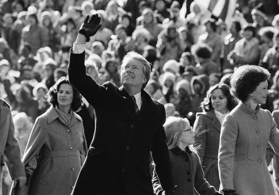 FILE - U.S. President Jimmy Carter waves to the crowd while walking with his wife, Rosalynn, and their daughter, Amy, along Pennsylvania Avenue. The Carters elected to walk the parade route from the Capitol to the White House following his inauguration in Washington, Jan. 20, 1977. Carter announced his campaign for the presidency in December 1974. At that point he had never met an American president. He later said part of what nudged him into the race was meeting several candidates ahead of the 1972 campaign and concluding that he was talented as they were. (AP Photo/Suzanne Vlamis, File)