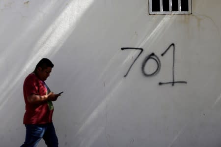 FILE PHOTO: A man walks by the number 701, referring to the world's billionaires ranking given by Forbes magazine in 2009 to Mexican drug lord Joaquin 'El Chapo' Guzman, ahead of the visit of Mexico's President Andres Manuel Lopez Obrador to Badiraguato