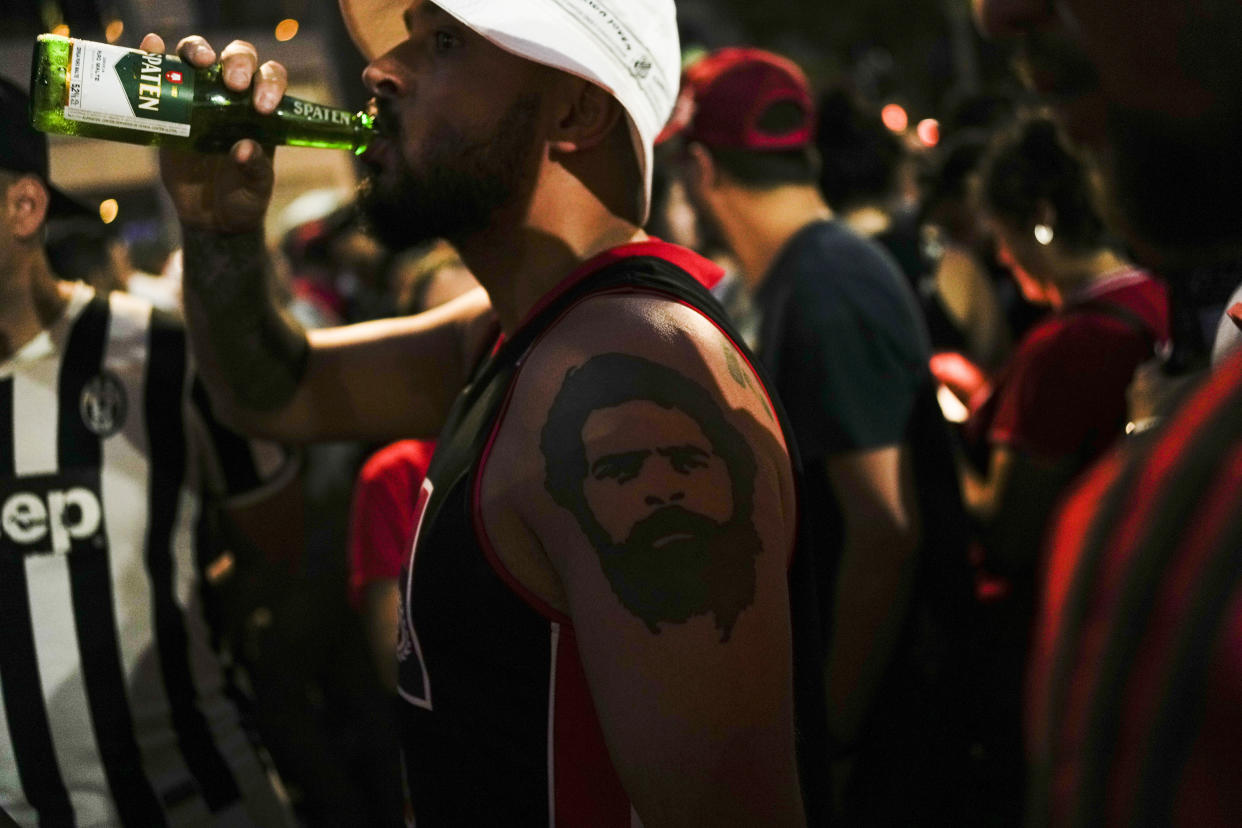 A supporter of Brazil's former President Luiz Inacio Lula da Silva, dons a tattoo of Lula on his forearm, as he waits for results after polls closed in the country's presidential run-off election, in Sao Paulo, Brazil, Sunday, Oct. 30, 2022. On Sunday, Brazilians had to choose between da Silva and incumbent Jair Bolsonaro, after neither got enough support to win outright in the Oct. 2 general election.(AP Photo/Matias Delacroix)