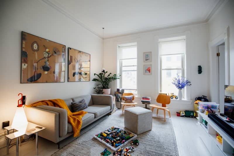 Kids toys spilled on patterned grey rug on living room floor.