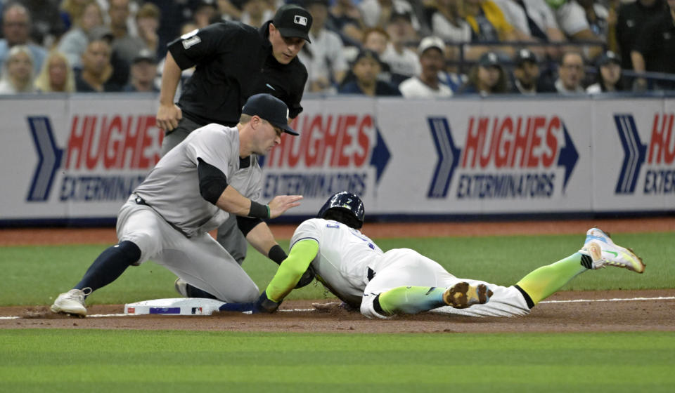 Umpire Quinn Wolcott watches New York Yankees' Jon Berti, left, tag out Tampa Bay Rays' José Caballero on an attempted steal of third base during the third inning of a baseball game Friday, May 10, 2024, in St. Petersburg, Fla. (AP Photo/Steve Nesius)
