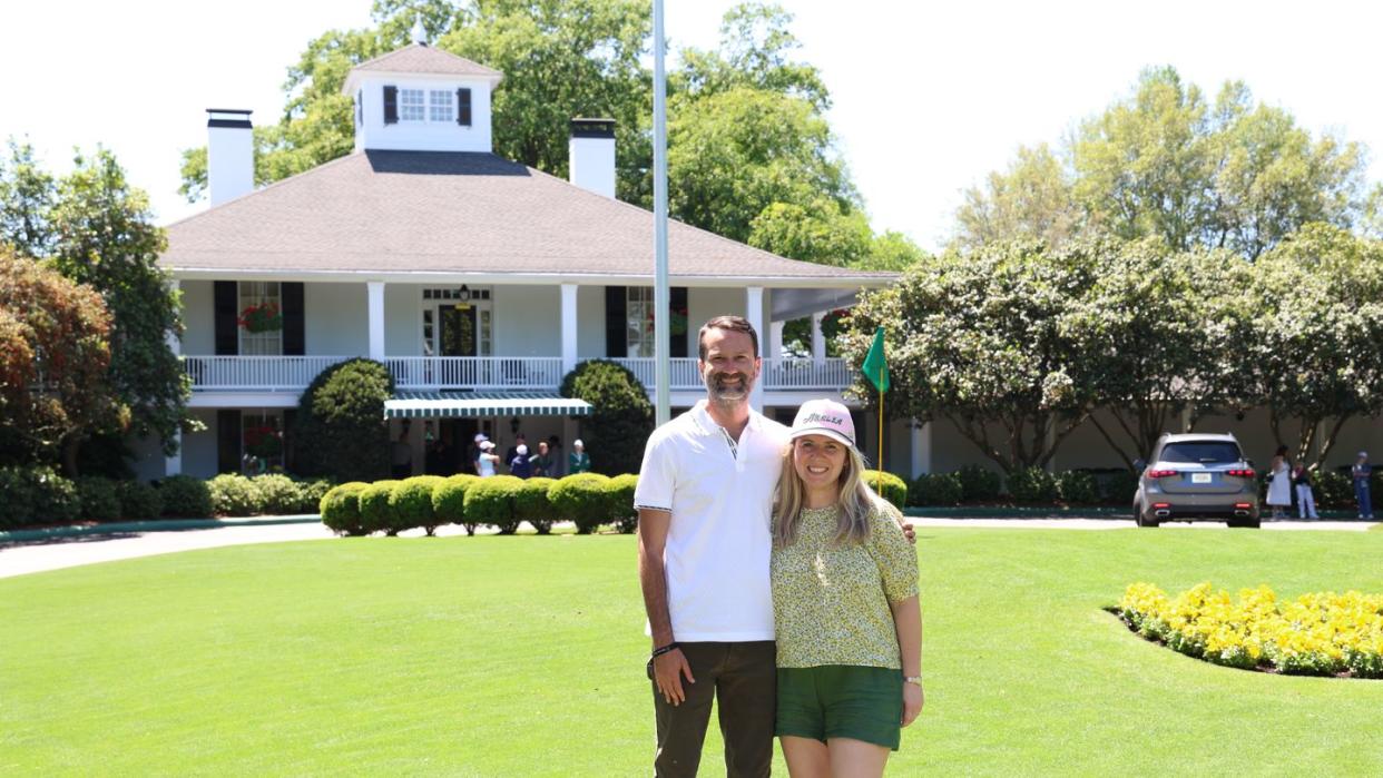 a couple posing in front of the clubhouse at augusta national golf club during the masters tournament