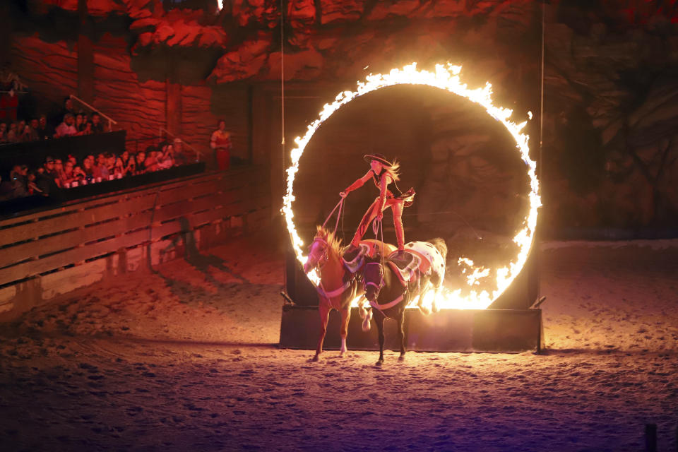 A woman rides horses through a ring of fire during Dolly Parton's Stampede dinner show on Aug. 26, 2022, in Branson, Mo. (Kit Doyle/RNS via AP)