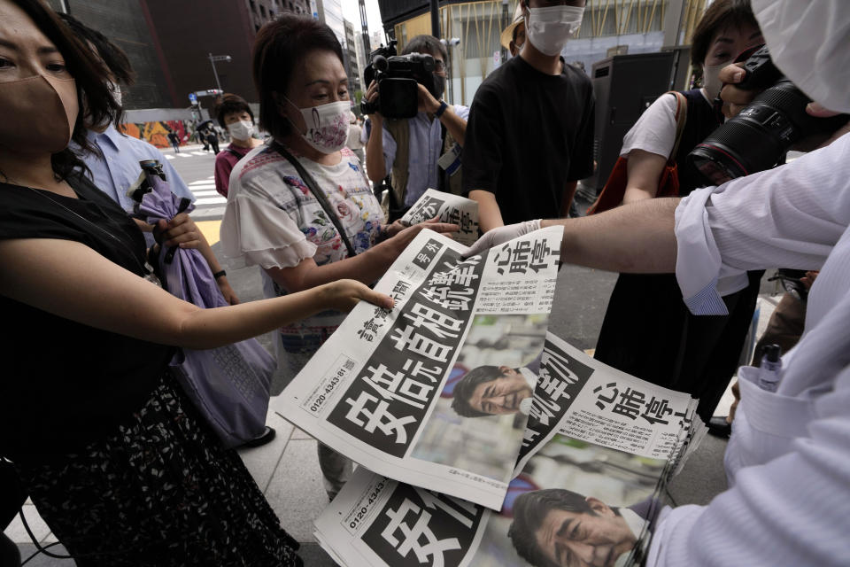 An employee distributes extra editions of the Yomiuri Shimbun newspaper reporting on Japan's former Prime Minister Shinzo Abe was shot, Friday, July 8, 2022, in Tokyo. Former Japanese Prime Minister Shinzo Abe, a divisive arch-conservative and one of his nation's most powerful and influential figures, has died after being shot during a campaign speech Friday in western Japan, hospital officials said. (AP Photo/Eugene Hoshiko)