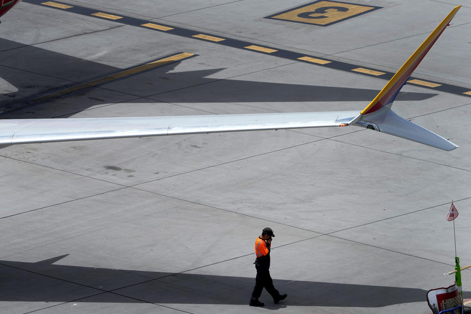 A member of the grounds crew wipes his face while under the wing of a jet at Sky Harbor International Airport on Monday, July 10, 2023, in Phoenix. (AP Photo/Matt York)