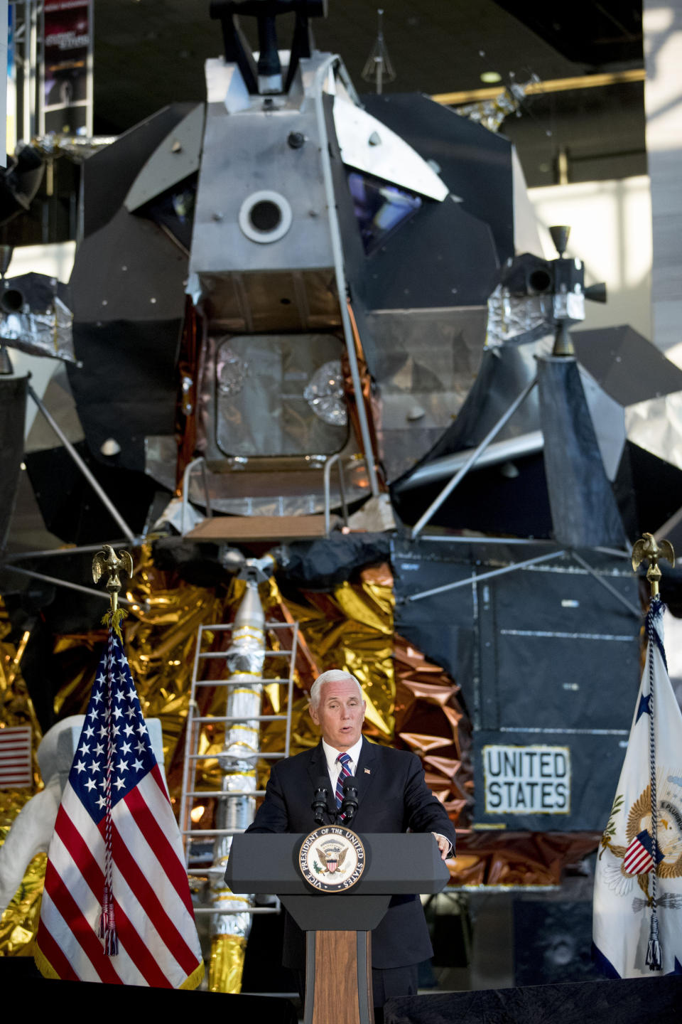 FILE - In this July 16, 2019 file photo, a lunar module, the same type that landed on the moon for Apollo 11, is displayed behind Vice President Mike Pence as he speaks before the unveiling of Neil Armstrong's Apollo 11 spacesuit at the Smithsonian's National Air and Space Museum on the National Mall in Washington. The White House wants U.S. astronauts on the moon by 2024, a scant five years from now. The moon will serve as a critical proving ground, the thinking goes, for the real prize of sending astronauts to Mars. (AP Photo/Andrew Harnik, File)