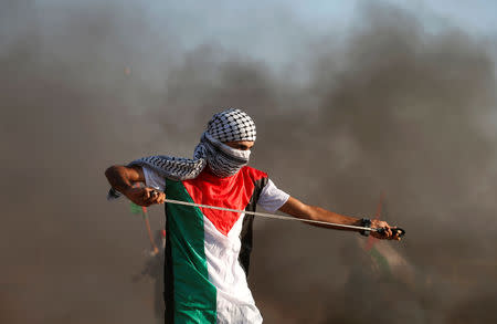 A Palestinian uses a sling to hurl stones at Israeli troops during a protest calling for lifting the Israeli blockade on Gaza and demand the right to return to their homeland, at the Israel-Gaza border fence, east of Gaza City September 14, 2018. REUTERS/Mohammed Salem