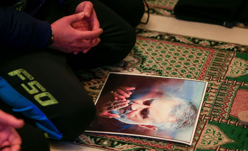 A man prays next to a picture of late Iranian Major-General Qassem Soleimani in Ghazieh