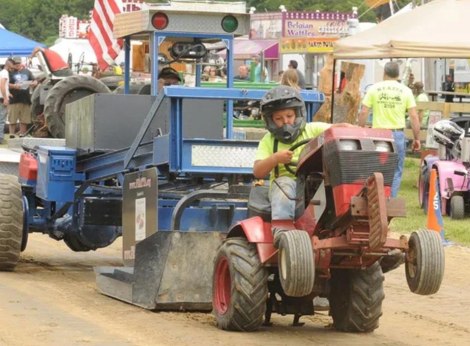 Joseph Machado of Warren, Rhode Island, gets some air under his front wheels as he pulls the 4,500 pounds riding on the transfer sled behind his lawn tractor during the 2014 Westport Fair.