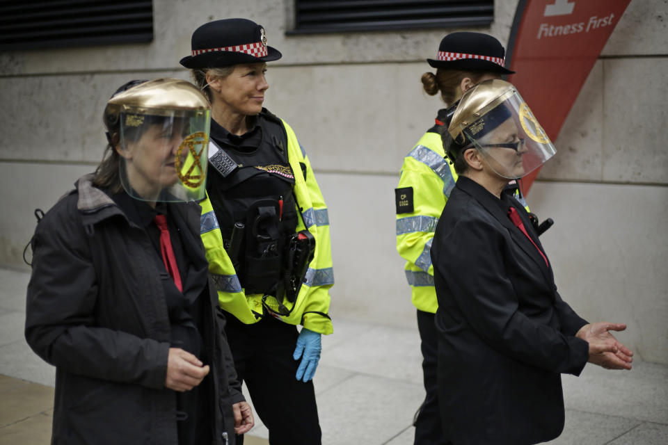 Extinction Rebellion climate change protesters who glued their hands to floors and walls of the London Stock Exchange are being led away by police in the City of London, Thursday, April 25, 2019. The non-violent protest group, Extinction Rebellion, is seeking negotiations with the government on its demand to make slowing climate change a top priority. (AP Photo/Matt Dunham)