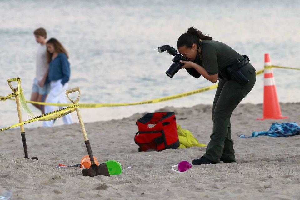 <p>Mike Stocker/South Florida Sun Sentinel/Tribune News Service via Getty</p> Investigators on the beach in Lauderdale-by-the-Sea take photos of the scene of a sand collapse on Tuesday, Feb. 20, 2024.