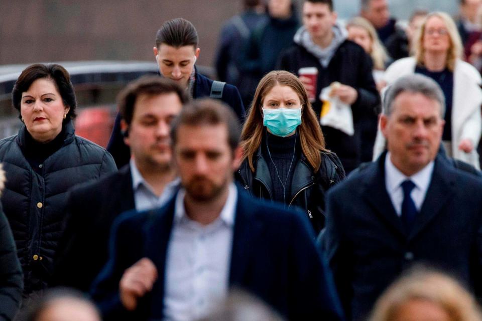 A London commuter wears a mask in a crowd of people (AFP via Getty Images)