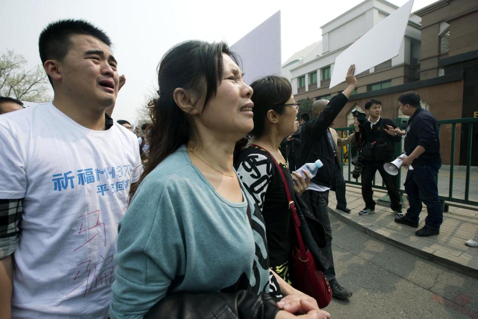 Dos familiares de los pasajeros chinos que viajaban en un avión desaparecido de Malaysia Airlines lloran durante una protesta el martes 25 de marzo de 2014 frente a la embajada de Malasia, furiosos de que Kuala Lumpur haya declarado muertos a sus seres queridos al afirmar que la aeronave se desplomó en un accidente, sin tener evidencia física alguna. (Foto AP/Ng Han Guan)