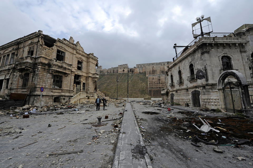 <p>People walk past the old customs buildings (left) and Peoria restaurant (right) near Aleppo’s historic citadel, in the government-controlled area of the city, Syria, Dec. 17, 2016. (Photo: Omar Sanadiki/Reuters) </p>