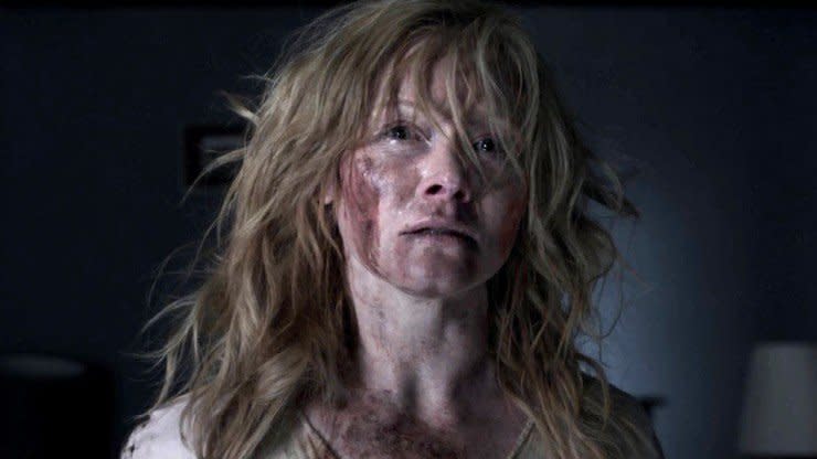 Amelia from babadook film stands with blood on her face and disheveled hair