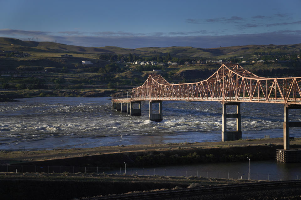 El agua del río Columbia fluye bajo el puente The Dalles, cerca de la represa del mismo nombre, que cruza la línea entre los estados de Washington y Oregon, el domingo 19 de junio de 2022. El río se ve amenazado por el cambio climático, la polución y la industrialización. (AP Foto/Jessie Wardarski)