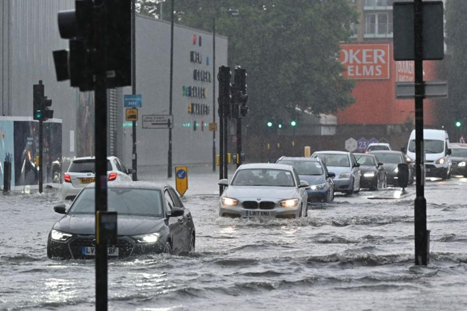 Cars drive through deep water on a flooded road in The Nine Elms in July 2021 (AFP via Getty Images)