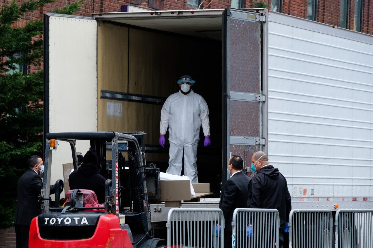 Workers place bodies of coronavirus victims in a cold storage truck outside Brooklyn Hospital Center in Brooklyn, New York on Tuesday, March 31, 2020.  