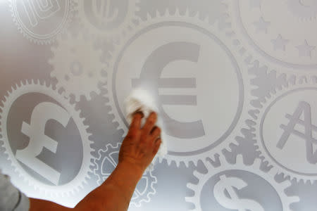 FILE PHOTO: A man cleans a board with different currency signs at a currency exchange office in Madrid, Spain, June 24, 2016. REUTERS/Susana Vera/File Photo