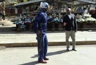 An armed riot policeman gestures to a pedestrian in Harare, Friday, Aug, 16, 2019. Zimbabwe's police patrolled the streets of Harare Friday morning while many residents stayed home and shops were shut fearing violence from an anti-government demonstration. Zimbabwe's High Court has upheld the police ban on the opposition protest.(AP Photo/Tsvangirayi Mukwazhi)