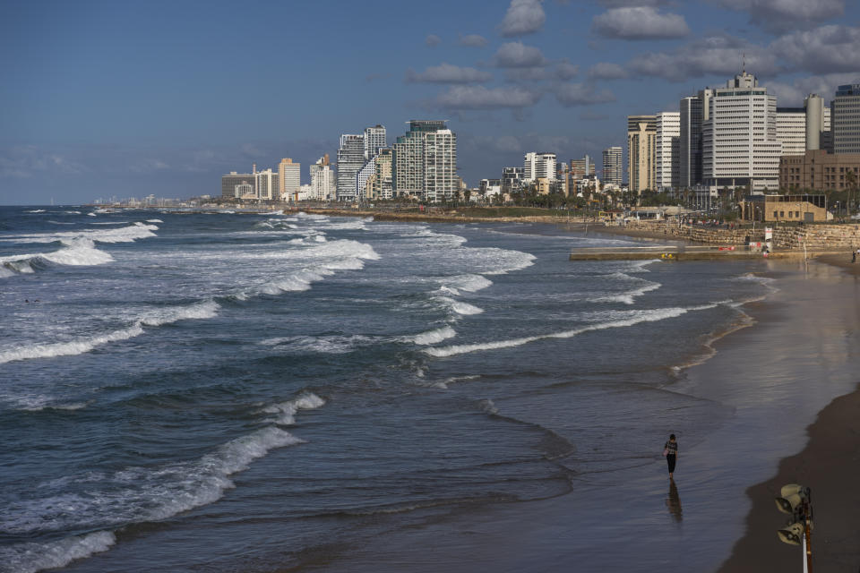 A woman walks on the Tel Aviv's Mediterranean Sea beachfront, Israel, Thursday, Dec. 2, 2021. Residents of Israel's seaside metropolis Tel Aviv have for years complained of how expensive it is, with living costs taking a chunk out of their paychecks. A report released Wednesday, Dec. 1, 2021, by the Economist Intelligence Unit, a research group linked to the Economist magazine, said Tel Aviv has emerged as the most expensive city to live in. (AP Photo/Oded Balilty)