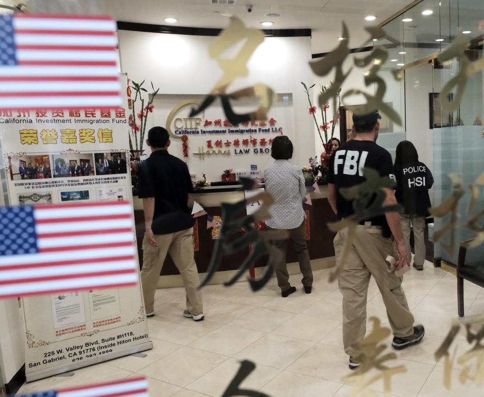 Federal agents enter California Investment Immigration Fund in San Gabriel, Calif., Wednesday, April 5, 2017. Federal authorities on Wednesday raided the Los Angeles-area business they say cheated a U.S. government visa program to obtain green cards for wealthy Chinese investors. (AP Photo/Rich Vogel