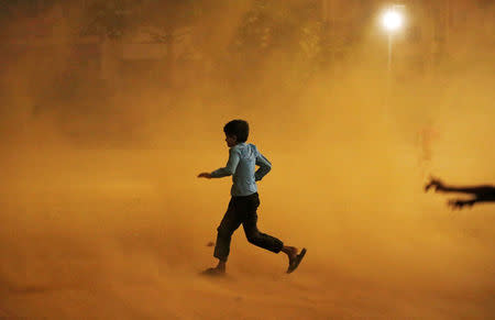 A boy runs for cover during a dust storm in New Delhi, India May 13, 2018. REUTERS/Adnan Abidi