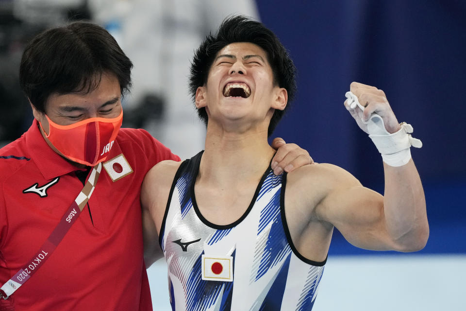 Daiki Hashimoto, of Japan, celebrates with his coach after winning the gold medal in the artistic gymnastics men's all-around final at the 2020 Summer Olympics, Wednesday, July 28, 2021, in Tokyo. (AP Photo/Gregory Bull)