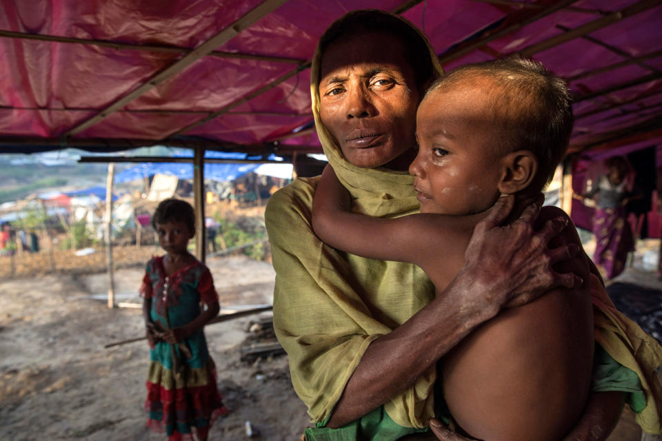 <p>Fleeing violence in Myanmar, Rohingya families arrive at Kutupalong. A Rohingya woman holds a young child in her makeshift tent at Kutupalong camp in Bangladesh on September 20, 2017. (Photograph by Paula Bronstein/UNHCR) </p>