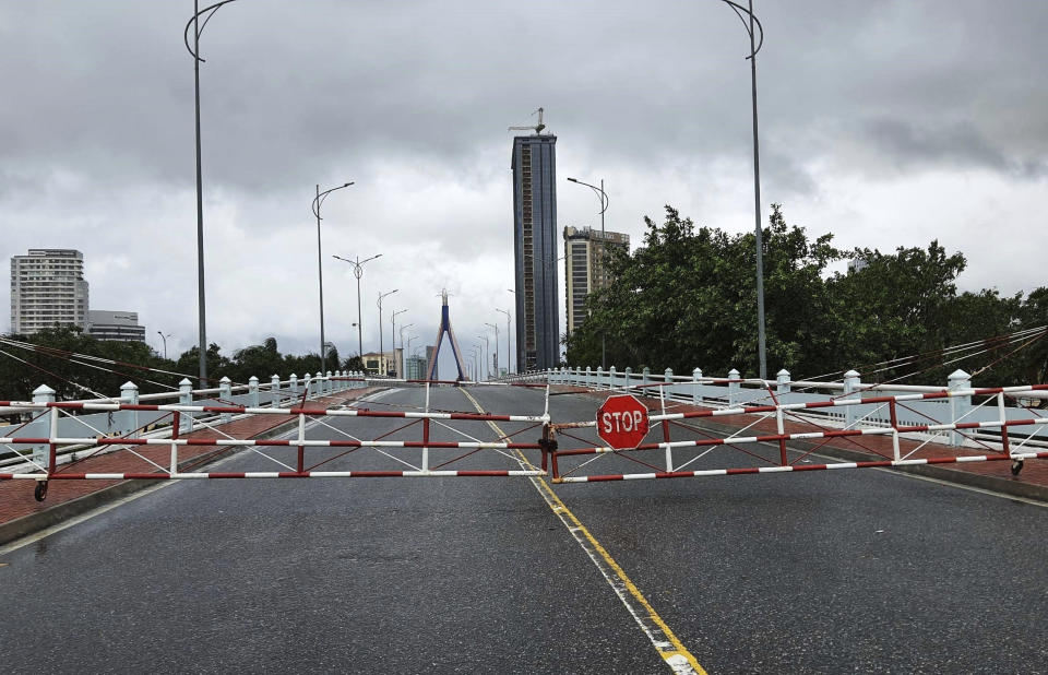 An empty street is barricaded ahead of Typhoon Molave in Da Nang, Vietnam Wednesday, Oct. 28, 2020. Typhoon Malove sank a few fishing boats as it approached Vietnam's south central coast on Wednesday morning. (Vo Van Dung/VNA via AP)