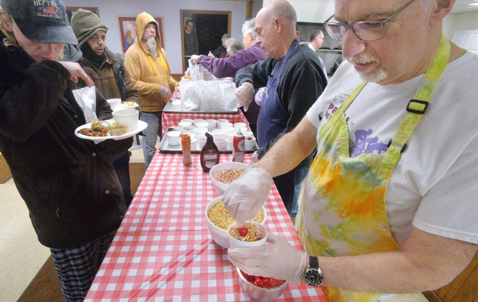 Emmaus Soup Kitchen volunteer John Fontecchio, 71, right, prepares ice cream sundaes for guests in Erie on Jan. 9, 2024. The soup kitchen has been serving meals for those in need in Erie for 50 years.