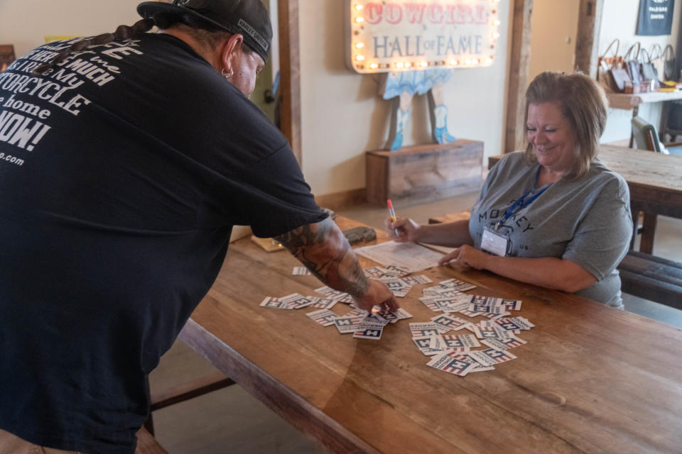 A rider reaches for his card Saturday at Sad Monkey Mercantile near Palo Duro Canyon during the Sixth Annual Homeless Heroes Bike Run.