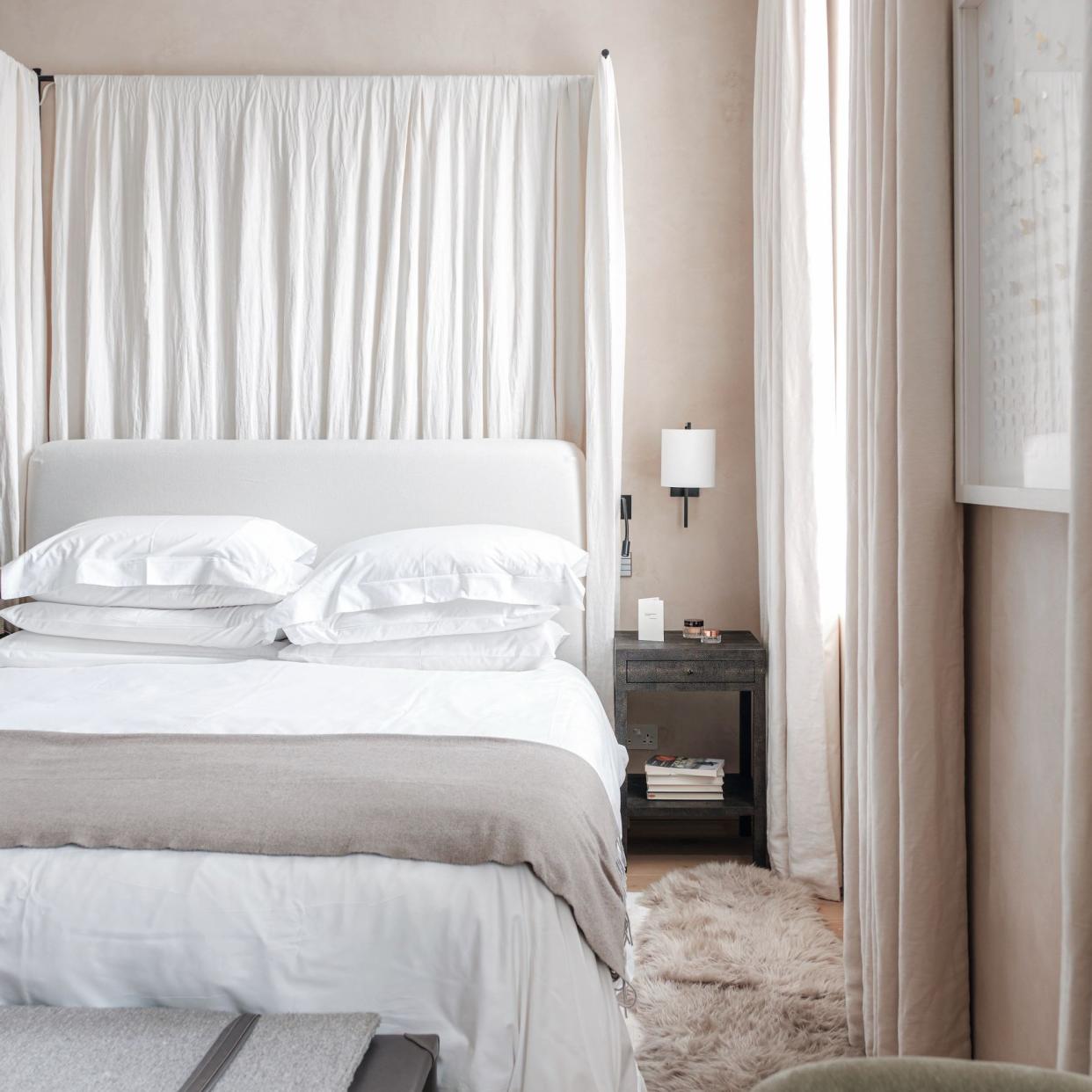  Bed with white duvet set in beige coloured bedroom. 