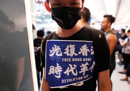 A demonstrator displays a placard as he attends a rally to support the city-wide strike and to call for democratic reforms at New Town Plaza shopping mall in Hong Kong