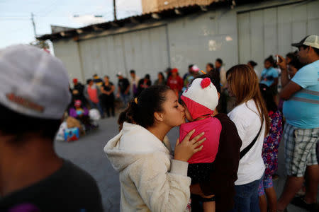 A member of a migrant caravan from Central America kisses a baby as they pray in preparation for an asylum request in the U.S., in Tijuana, Baja California state, Mexico April 28, 2018. REUTERS/Edgard Garrido