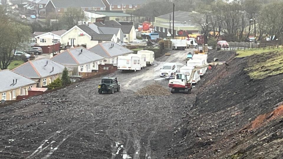 A number of caravans parked next to diggers undertaking work