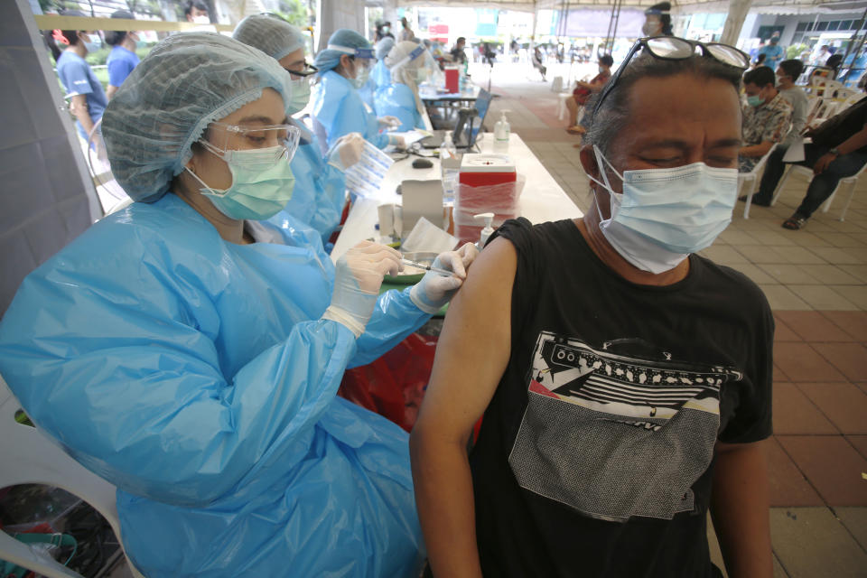 In this Tuesday, May 4, 2021, photo, a health worker administers a dose of the Sinovac COVID-19 vaccine to residents of the Klong Toey area, a neighborhood currently having a spike in coronavirus cases, in Bangkok, Thailand. Health officials rushed to vaccinate thousands of people in Bangkok's biggest slum on Wednesday as a new surge in COVID-19 cases spread through densely populated low-income areas located in the capital's central business district.(AP Photo/Anuthep Cheysakron)