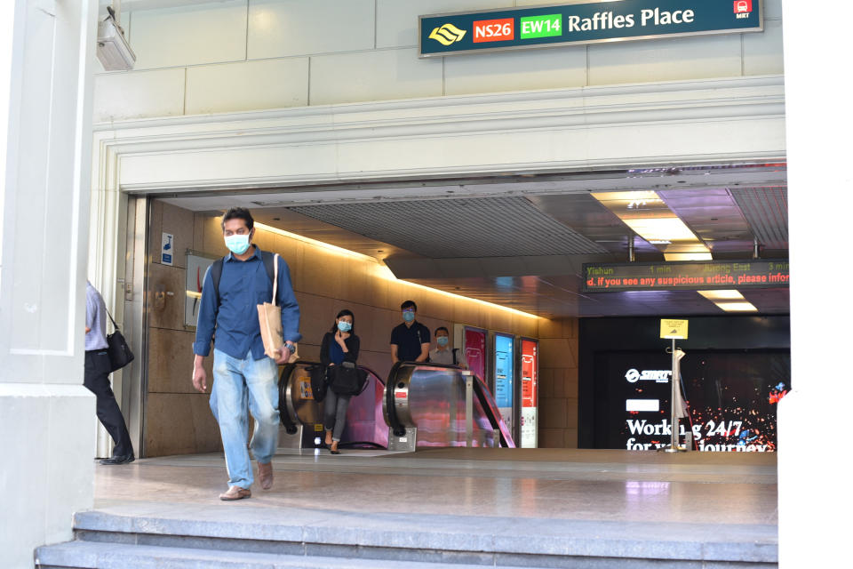 Subway commuters emerge from the Raffles Place MRT exit in Singapore Tuesday, June 2, 2020. Singapore reopened 75 percent of its economy Tuesday, as part of a three-phase controlled approach to end a virus lockdown since early April. (AP Photo/YK Chan)