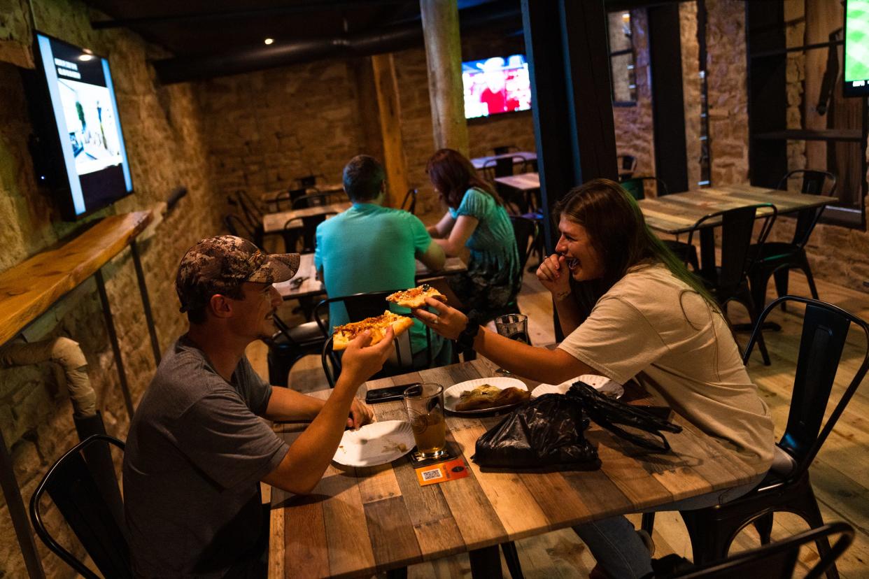 Patrick Kidwell, left, and Lydia Williams share pizza and beer at Speak Cheesy in downtown Fort Collins on June 21.