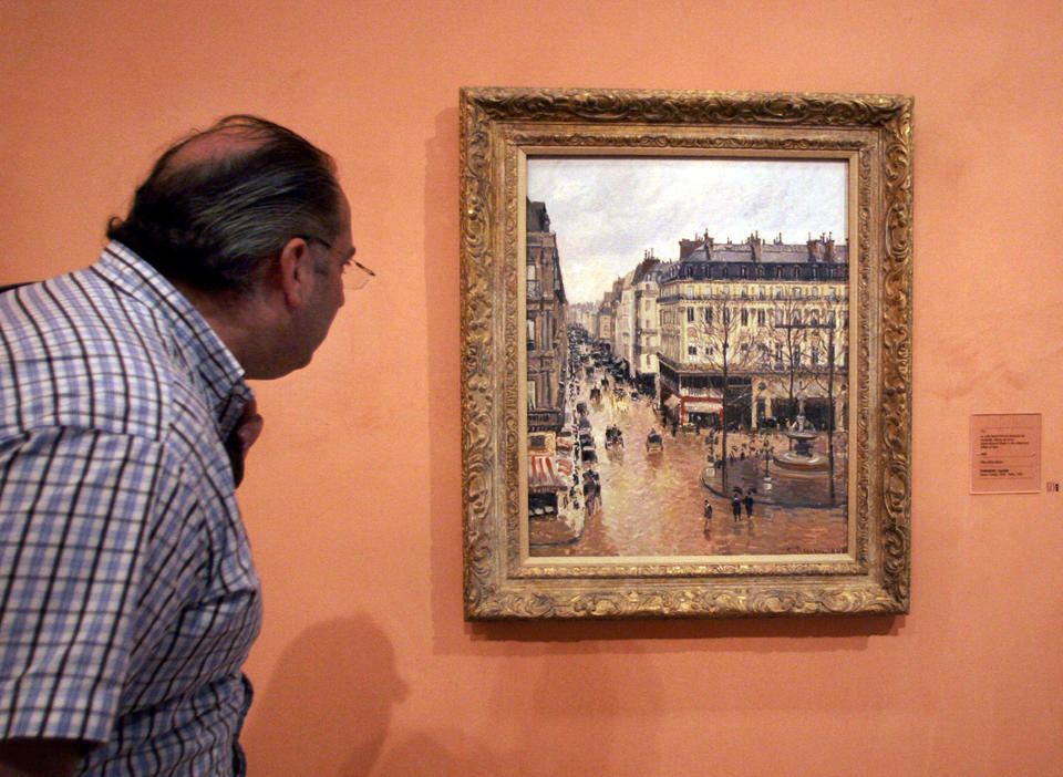 FILE - This May 12, 2005 file photo shows an unidentified visitor viewing the Impressionist painting called "Rue St.-Honore, Apres-Midi, Effet de Pluie" painted in 1897 by Camille Pissarro, on display in the Thyssen-Bornemisza Museum in Madrid. Lilly Cassirer surrendered her family's priceless Camille Pissarro painting to the Nazis in exchange for safe passage out of Germany during the Holocaust. The Supreme Court is hearing the case about the stolen artwork now in the collection of a Spanish museum in Madrid. (AP Photo/Mariana Eliano, File)