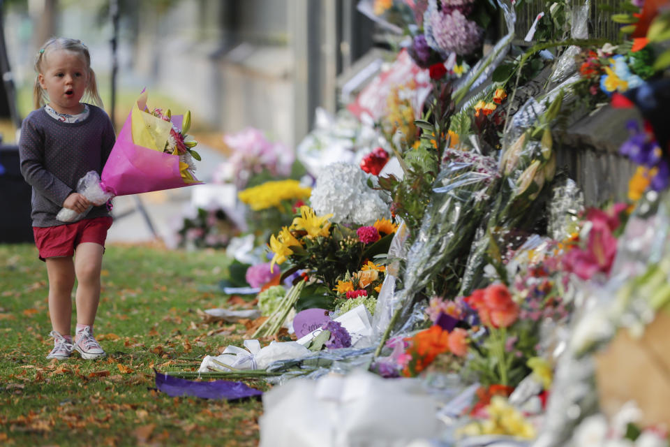 A girl carries flowers to a memorial wall following the mosque shootings in Christchurch, New Zealand. Source: AAP