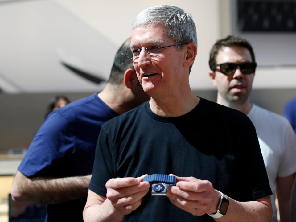 Apple CEO Tim Cook holding an Apple Watch