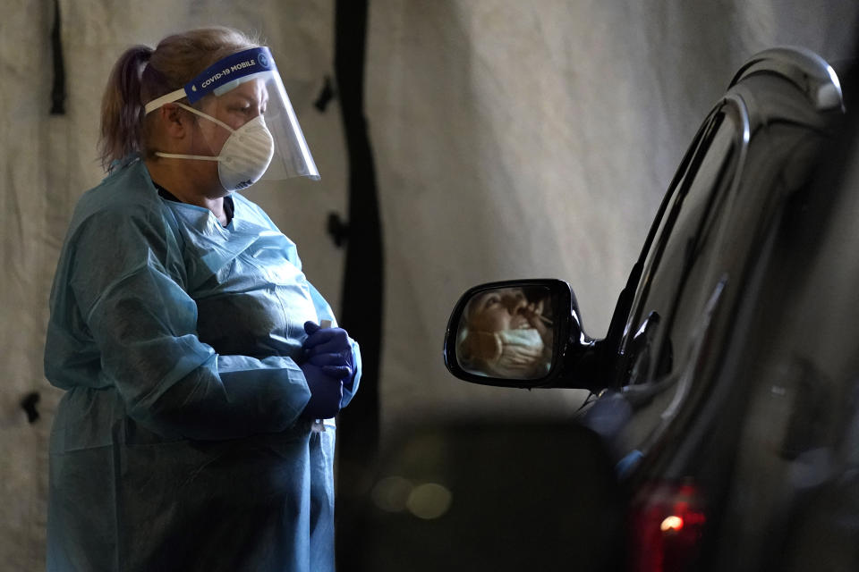 A healthcare worker watches as a patient uses a swab at a mobile testing location for COVID-19, Tuesday, Dec. 8, 2020, in Auburn, Maine. More than 14,000 Mainers have been diagnosed with the disease and 239 have died. (AP Photo/Robert F. Bukaty)