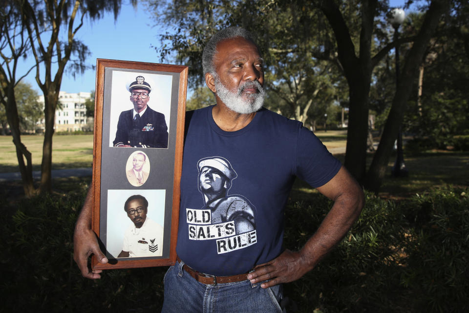 Reuben Green, a retired Black Naval officer, holds photos of, from bottom, his father, grandfather and himself, top, at Memorial Park in Jacksonville, Fla., Friday, Feb. 26, 2021. (AP Photo/Gary McCullough)