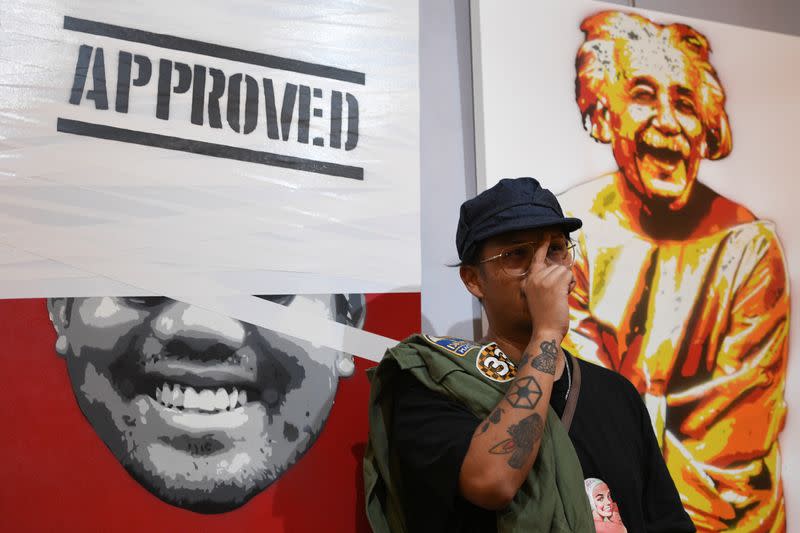 Headache Stencil, a graffiti artist poses in front of his works during his exhibition at The Foreign Correspondents' Club of Thailand (FCCT) in Bangkok
